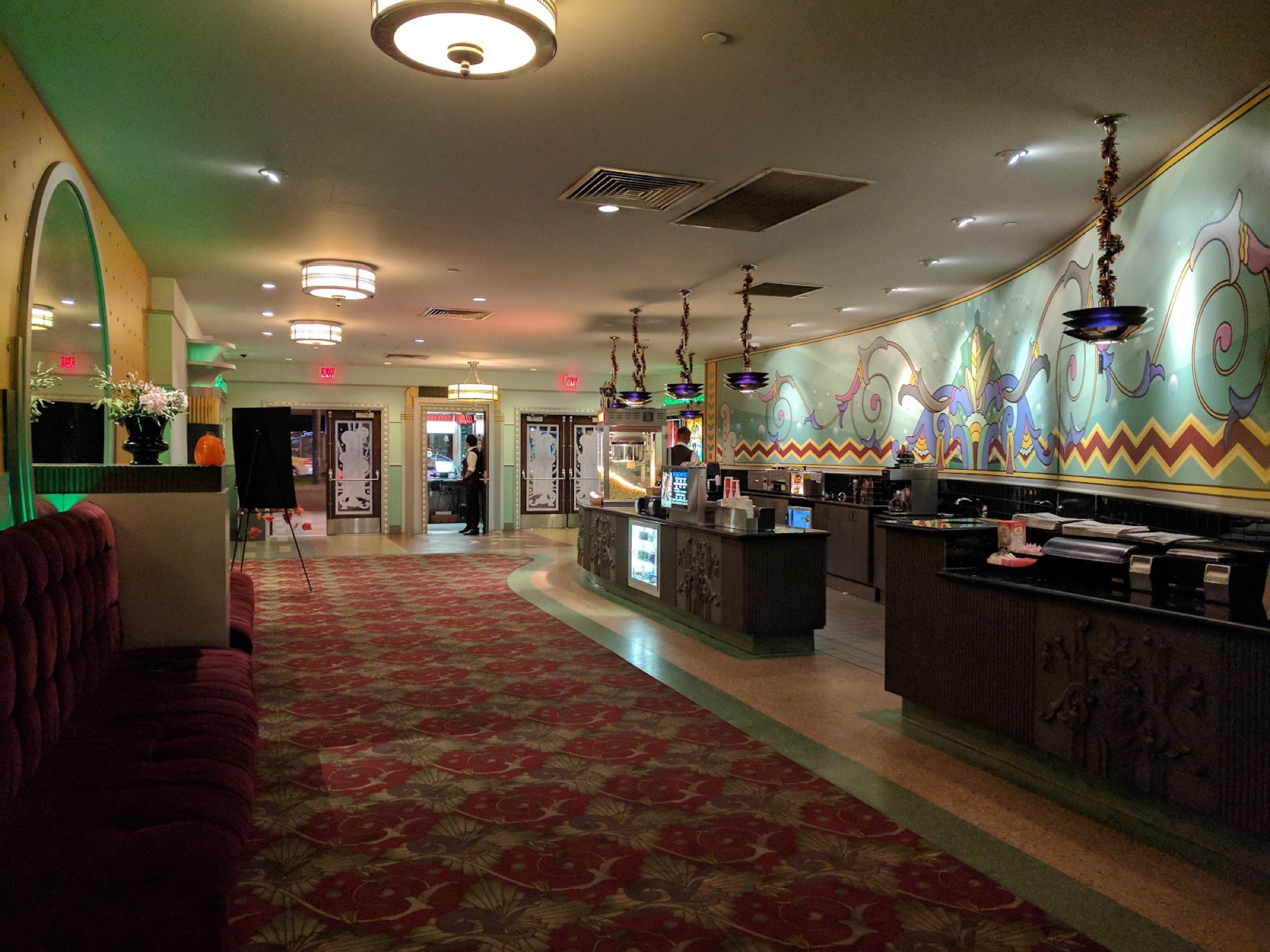 The Village Theatres lobby and concession stand with a sweeping curved Art Deco mural above the candy counter